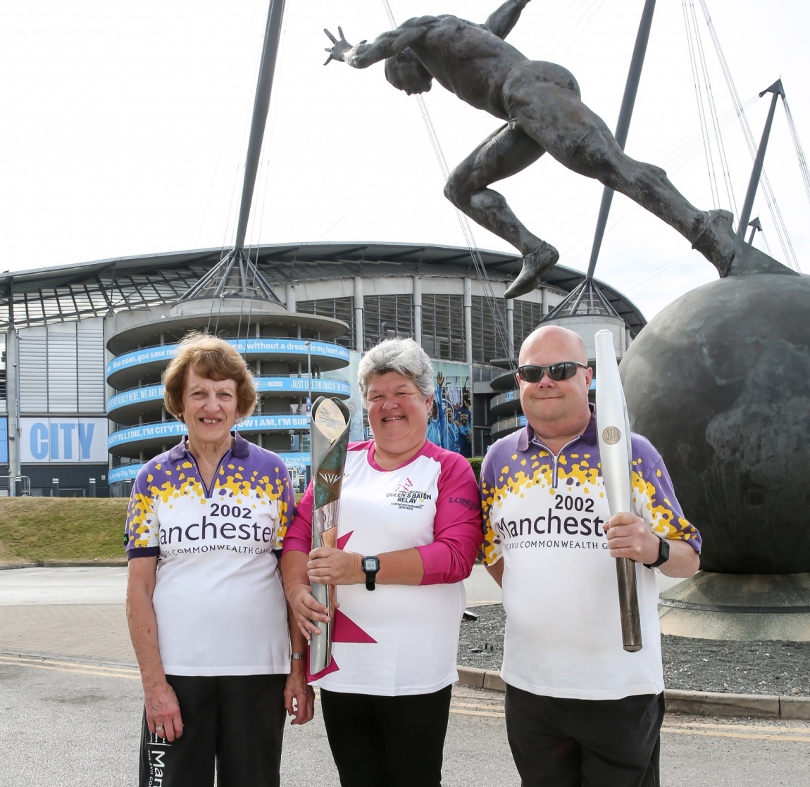 3 people stood outside the etihad stadium for the common wealth games