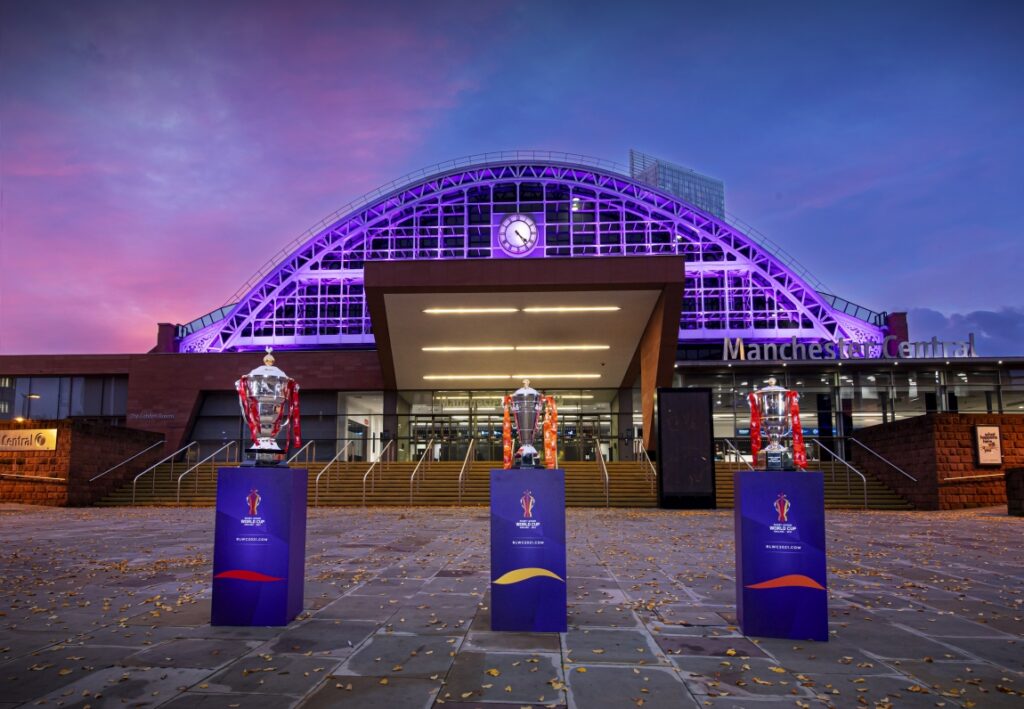 Three trophies on stands with a rugby stadium in the background