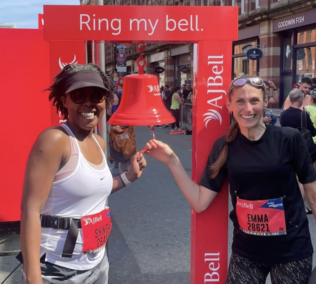 Two women ringing a bell at the end of a marathon