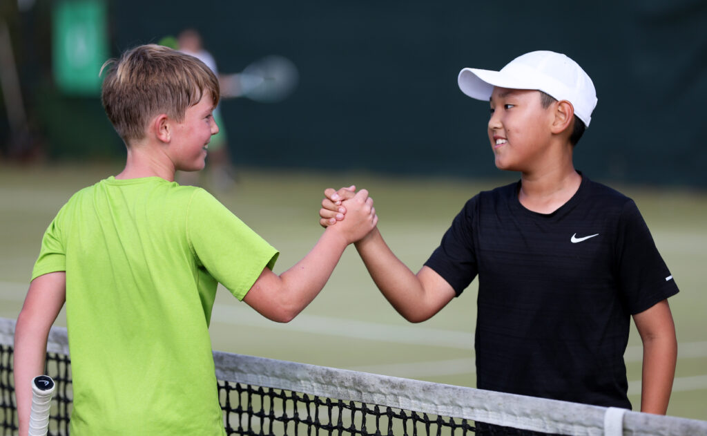 two boys shaking hands after tennis match