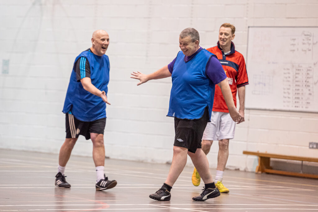 Older men playing football indoors
