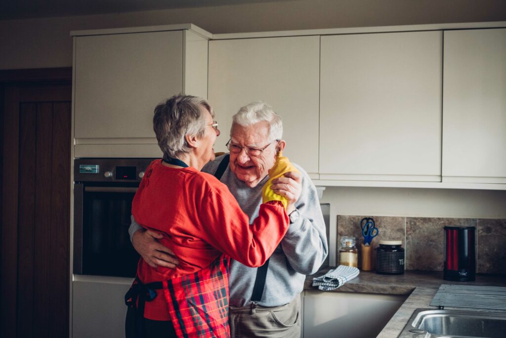 Two older people dancing in a kitchen