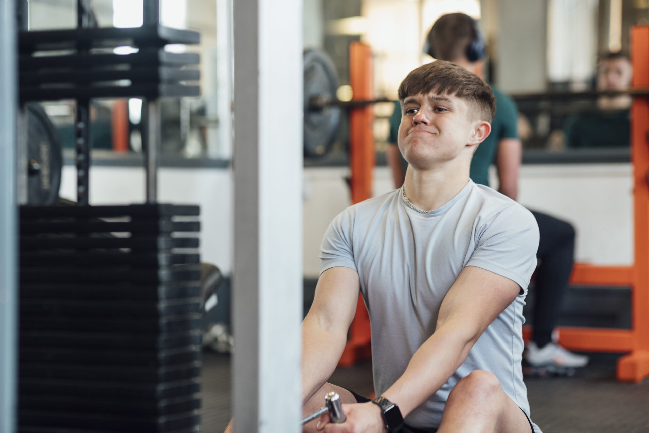 A young caucasian man weight resistance training in his local gym. He is wearing sports clothing and is training in an indoor gym.