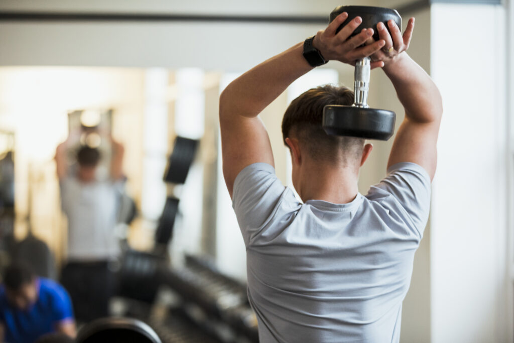 A young caucasian boy weight resistance training in his local gym. He is wearing sports clothing and is training in an indoor gym.