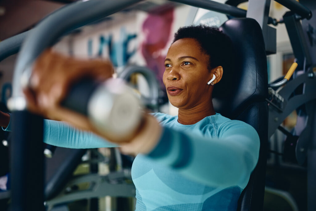 Athletic woman doing weight exercises for upper body strength during sports training in a gym.