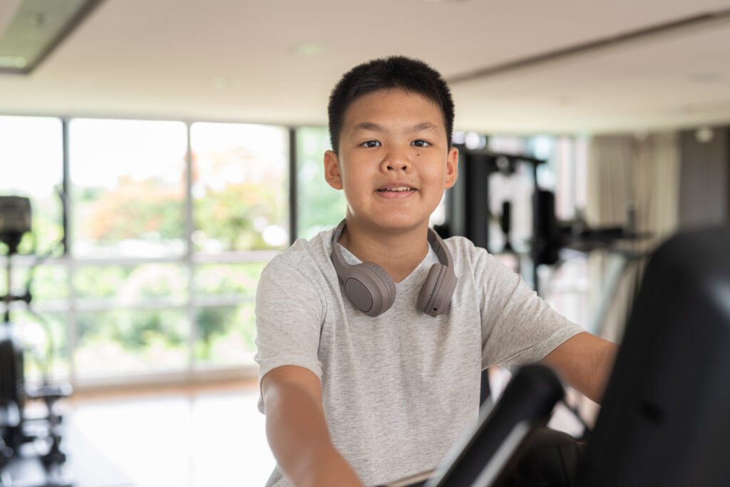 Young Asian Teen Boy Working Out on Exercise Bike