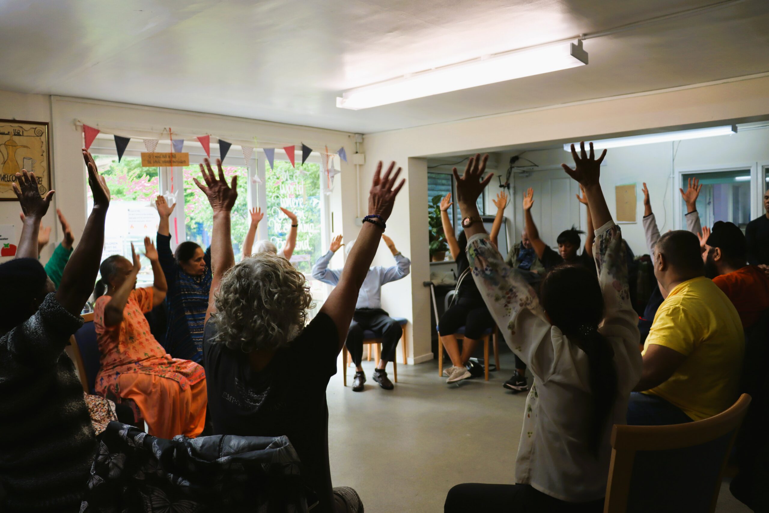Group of with arms in air doing chair based exercise